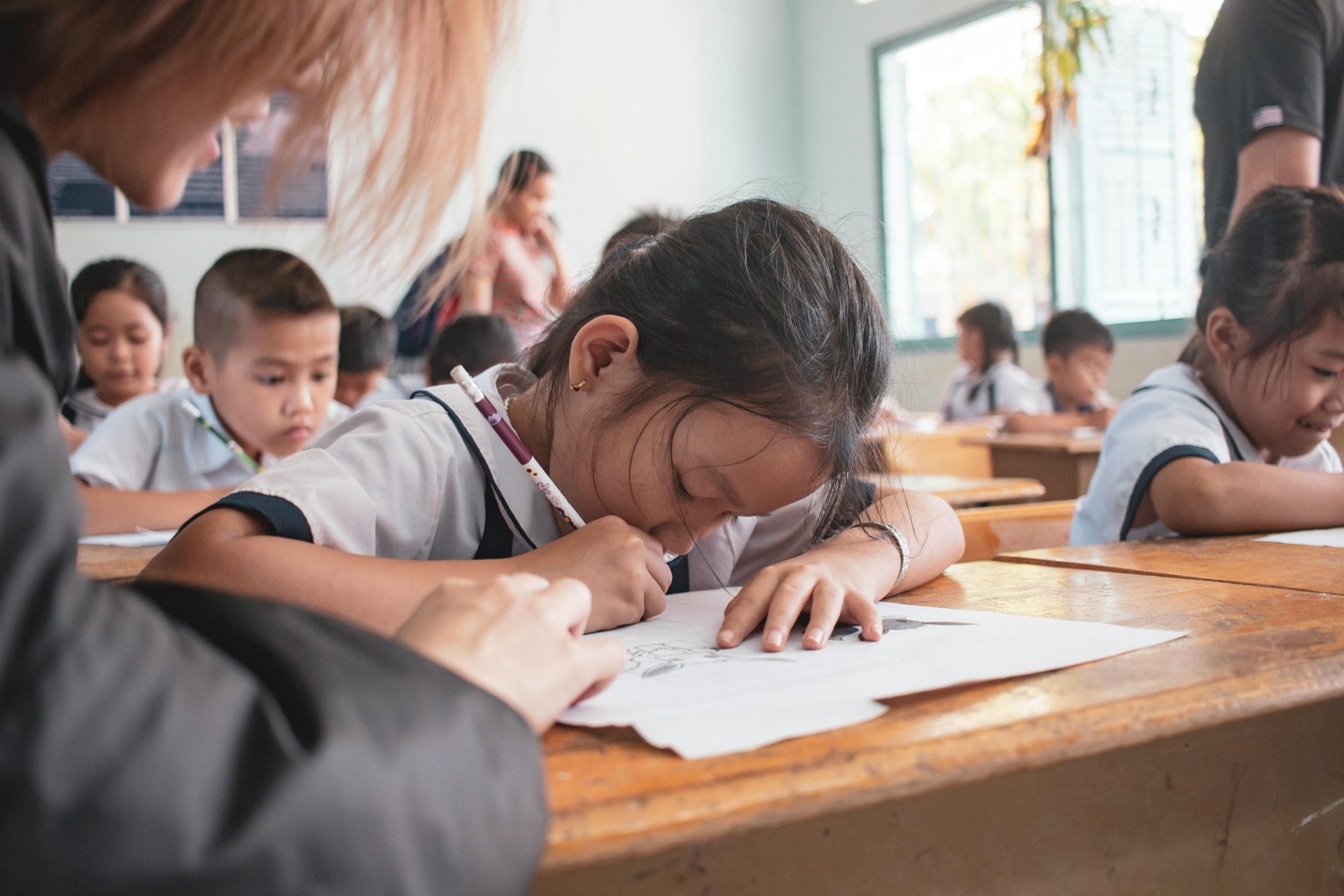 Children engaged in a classroom activity, focused on writing and learning.